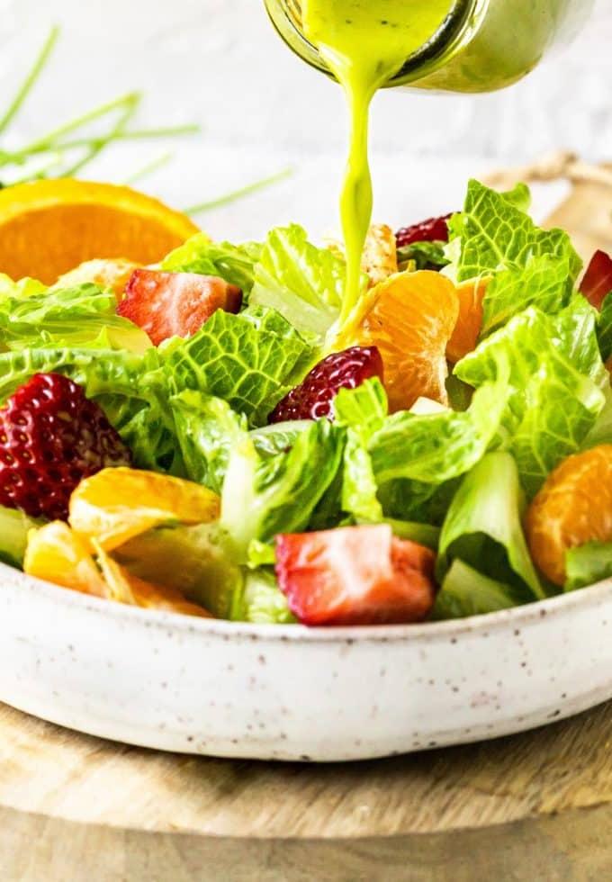 Eine Schüssel mit frischem Koriander-Zitrus-Vinaigrette und frischen Orangen und Limetten im Hintergrund