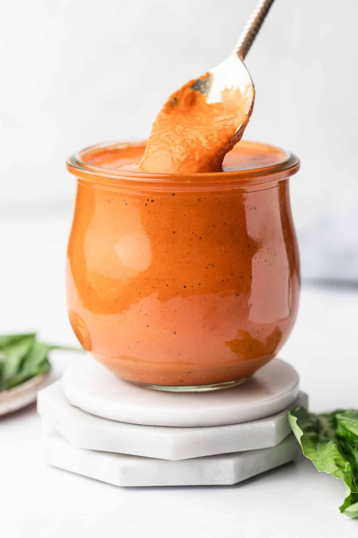 5-Minuten-cremige geröstete rote Paprika-Soße 2 Eine cremige, leuchtend rote geröstete Paprikasauce in einer kleinen weißen Schüssel, garniert mit frischem Basilikum.