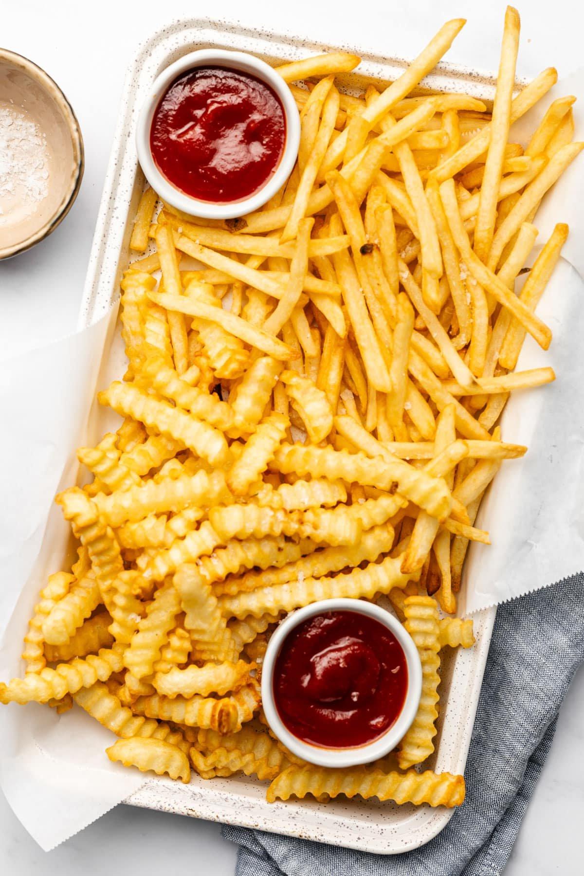 Tiefkühl-Pommes aus der Heißluftfritteuse 2 Knusprige Tiefkühl-Pommes aus der Heißluftfritteuse in einem Korb.