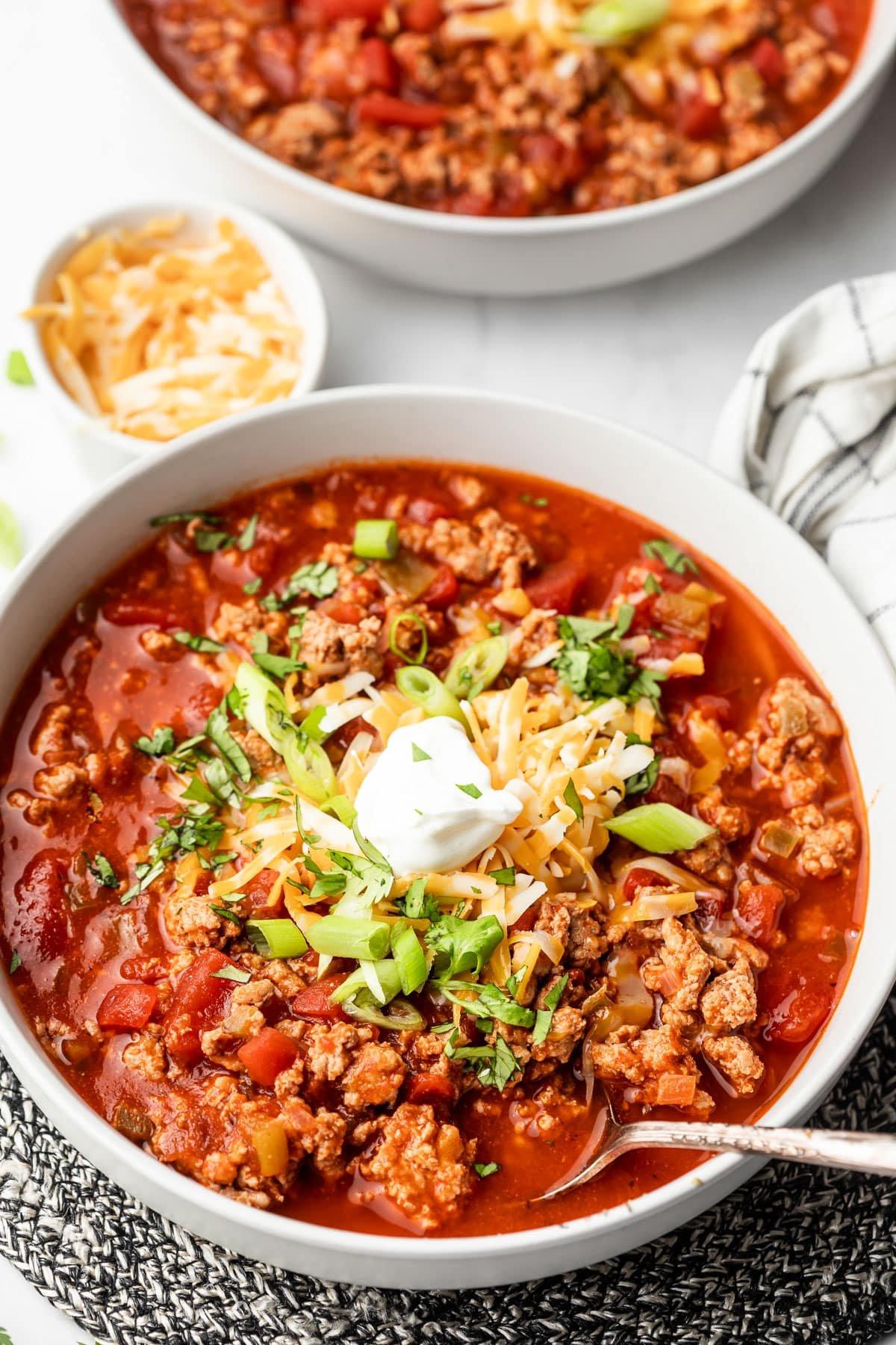 Das beste bohnenfreie kohlenhydratarme Puten-Chili 2 Ein Teller mit Low-Carb Truthahn-Chili, garniert mit Sauerrahm und frischen Kräutern