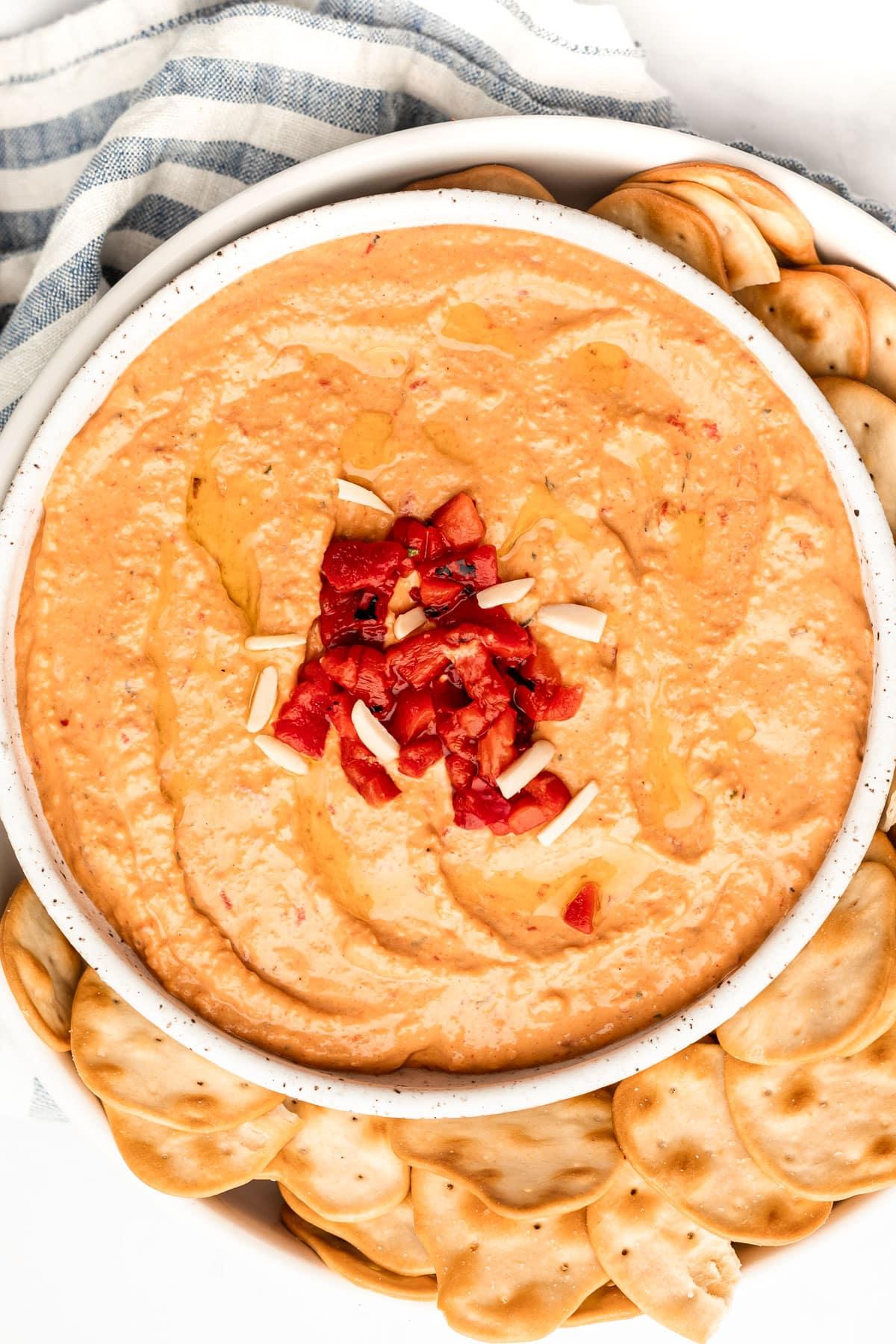 **Gerösteter Rote Paprika Hummus** 2 Frisch zubereiteter cremiger Rote-Paprika-Hummus in einer Schale, garniert mit Olivenöl und Paprika.
