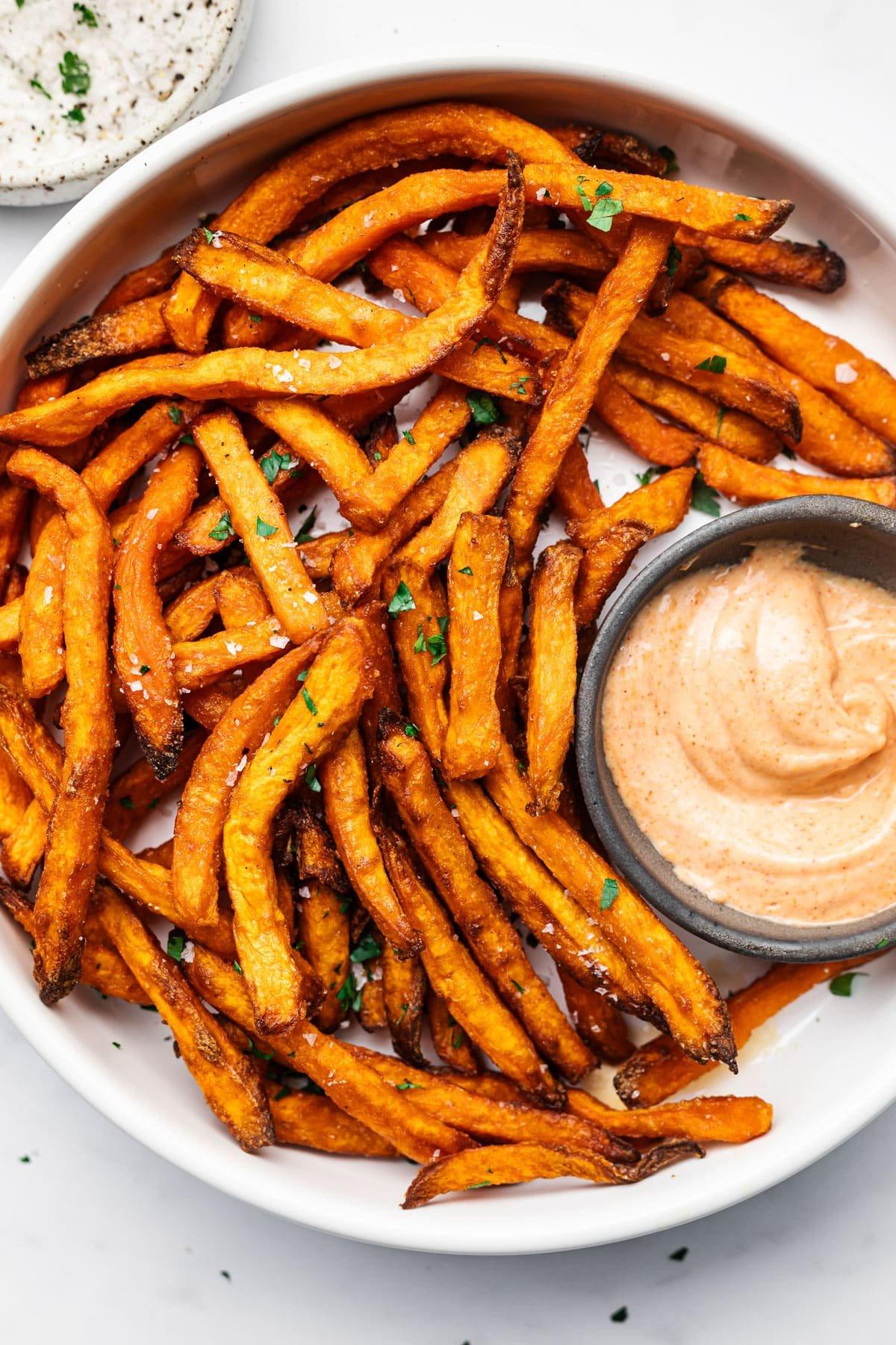 Tiefkühl-Süßkartoffel-Pommes aus der Heißluftfritteuse 2 Frisch zubereitete knusprige Süßkartoffelpommes auf einem Teller, perfekt goldbraun und leicht gesalzen, serviert als leckere Beilage.