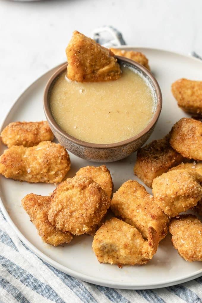 Gebackene Mandel-Hähnchen-Nuggets 2 Ofenfrische, goldbraun gebackene Hähnchen-Nuggets mit Mandelmehl auf einem Backblech