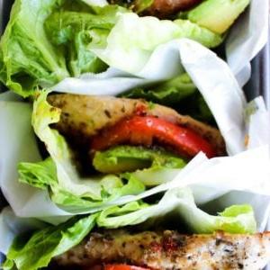 Salat-Wraps mit italienisch mariniertem Hähnchen 2 Hähnchen-Salatwickel mit italienischer Marinade, gefüllt mit gegrilltem Hähnchen, Tomaten, Zwiebeln und Avocado.