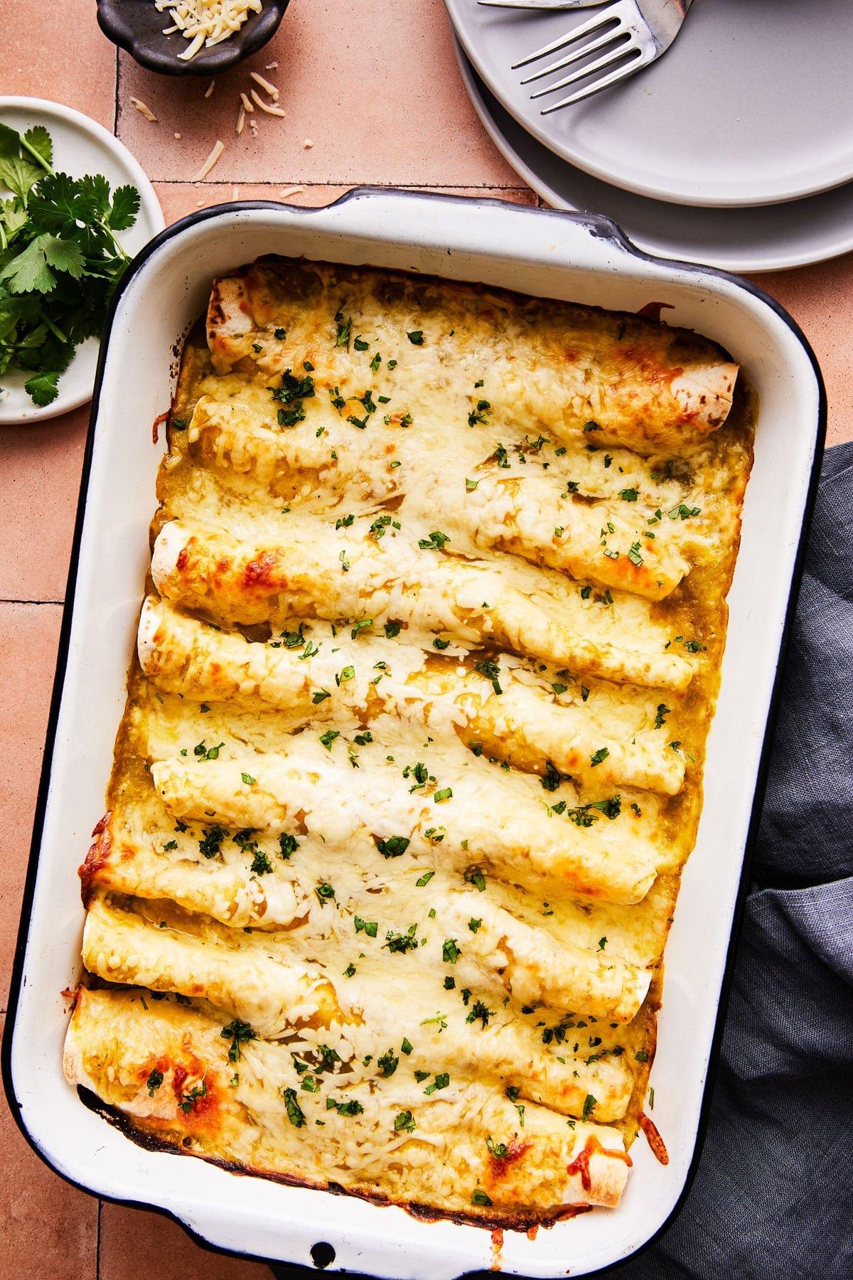 Frisch gebackene Salsa Verde Hähnchen-Enchiladas in einer Auflaufform, goldbraun mit geschmolzenem Käse und grüner Salsa