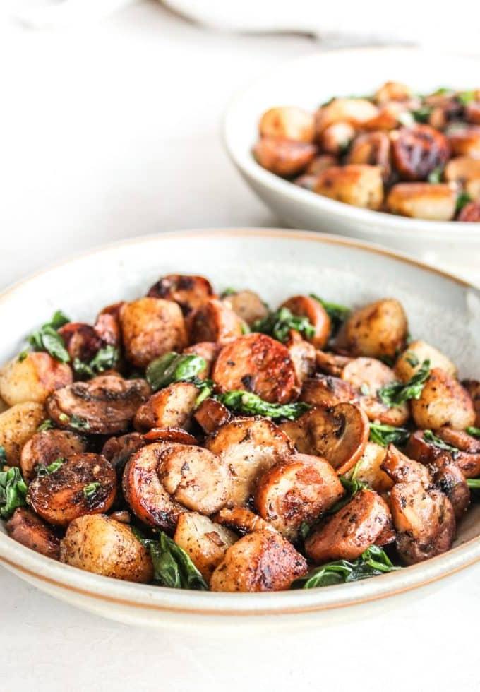 Pfannengebratenes Blumenkohl-Gnocchi mit Wurst, Pilzen und Spinat in einer Pfanne