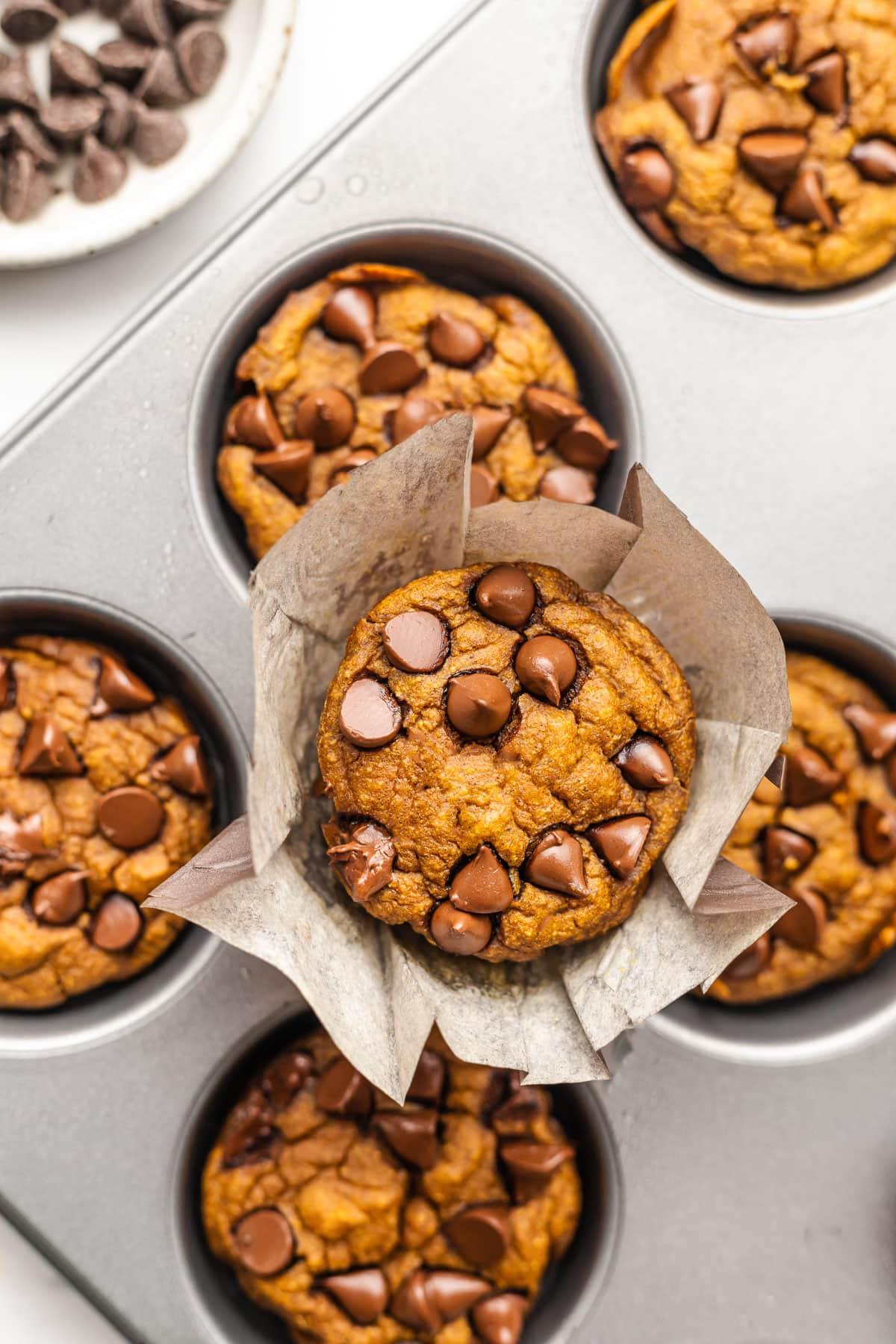 Frisch gebackene gesunde Kürbis-Haferflocken-Muffins mit Schokostückchen auf einem rustikalen Holzbrett