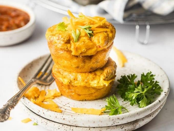 Zwei Rindfleisch-Cheddar-Eier-Muffins auf einem Teller mit frischen Beeren.