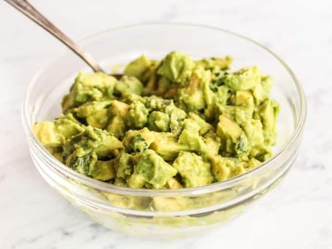 Frisch gewürfelte Avocado, gehackter Koriander und Limettenschnitze in einer Schüssel, bereit für das Topping.