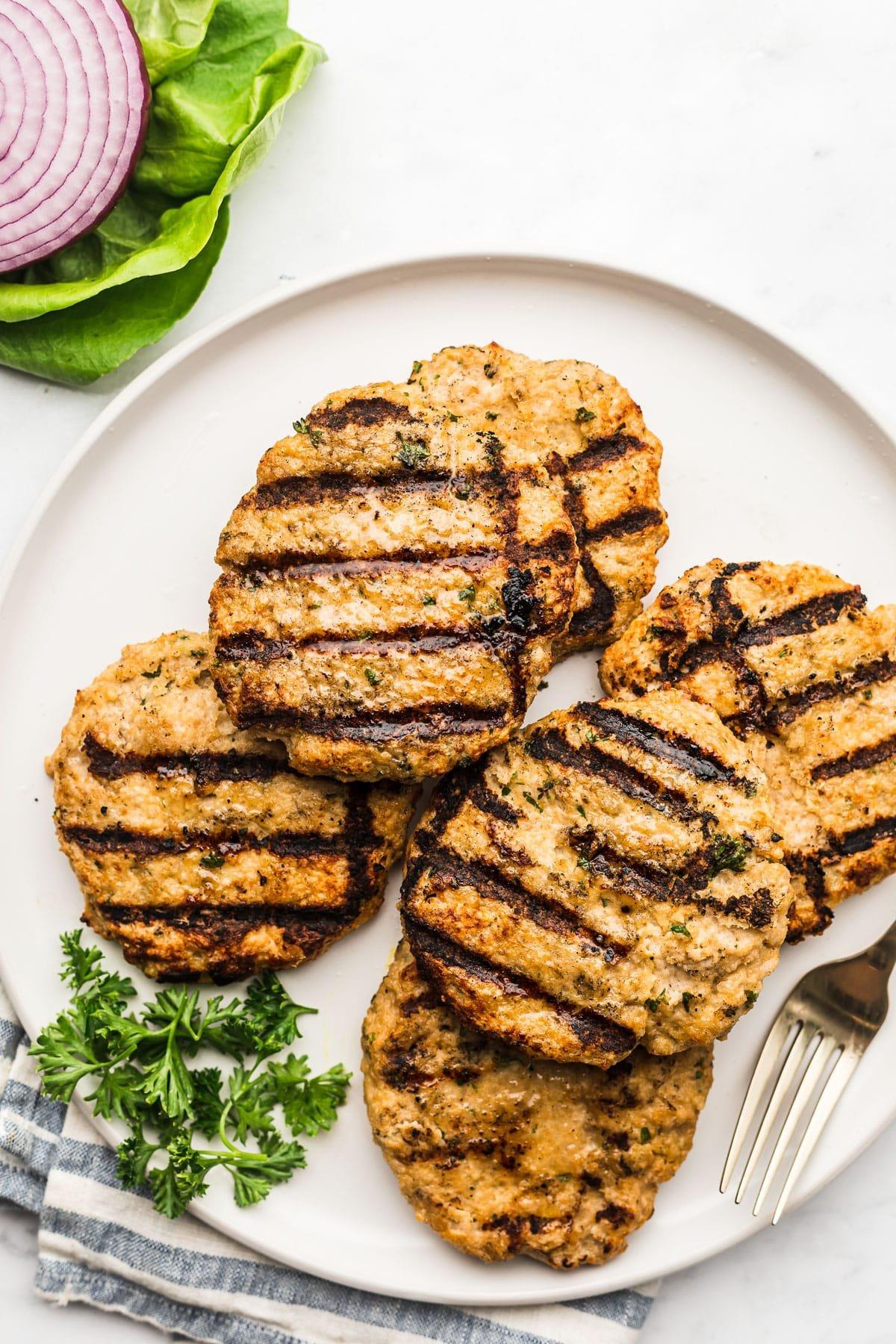Die besten Hähnchenhackfleisch-Burger 3 Fertig geformte Hähnchen-Hackfleisch-Patties auf einem Teller, bereit zum Grillen.