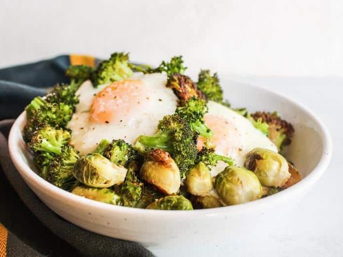 Vegetarische Frühstücks-Bowls vom Backblech 3 Fertige Blechpfannen-Frühstücks-Bowls angerichtet mit geröstetem Gemüse und gebackenen Eiern