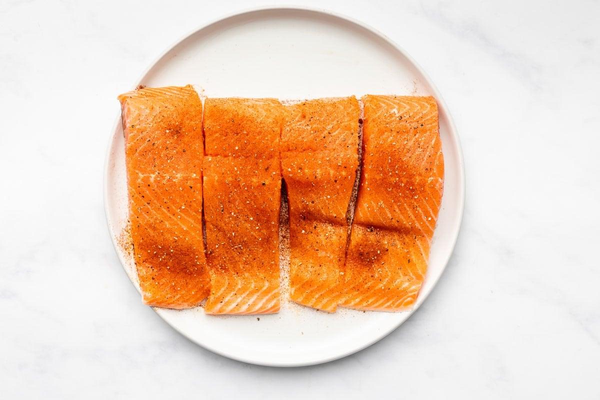 Einfacher scharf angebratener Chipotle-Limetten-Lachs 3 Zwei Stücke gebratener Lachs auf einem Teller, garniert mit frischer Petersilie und Limettenscheiben.