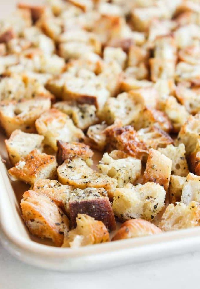 Hausgemachte Croutons 3 Frisch geschnittene Brotwürfel, gleichmäßig auf einem Schneidebrett verteilt, bereit für die Würzung.