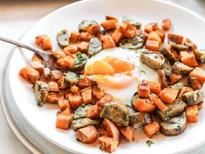 Süßkartoffel-Frühstück vom Blech 3 Süßkartoffel- und Würstchenmischung auf dem Backblech vor dem Hinzufügen der Eier