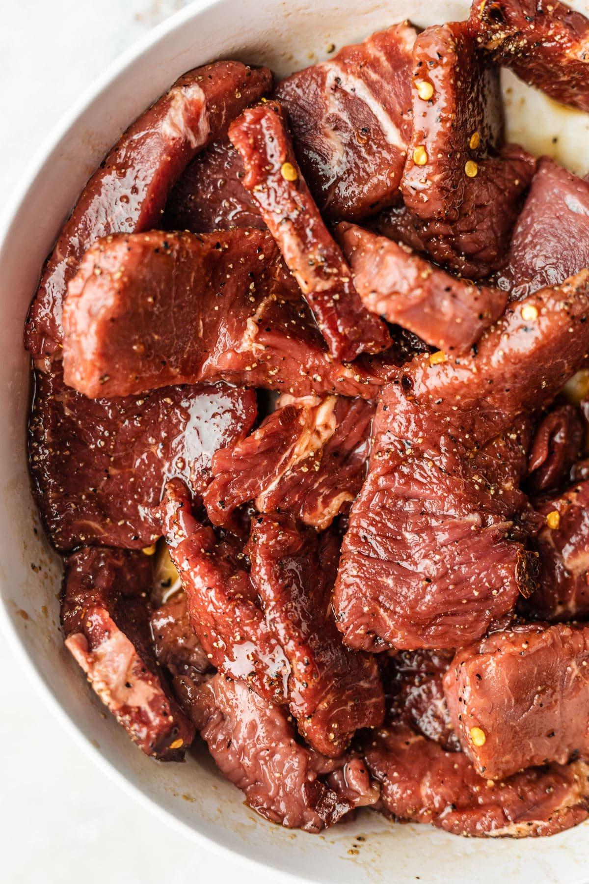 Steak mit geröstetem Gemüse 3 Nahe Aufnahme des marinierten Steaks und der vorbereiteten Gemüsesorten für das Backblech