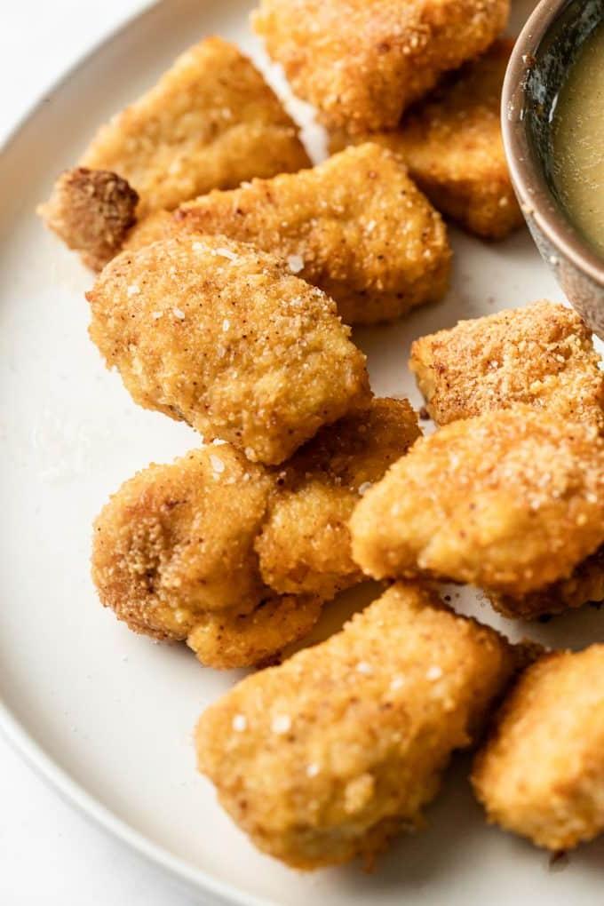 Gebackene Mandel-Hähnchen-Nuggets 3 Eine Nahaufnahme von knusprig panierten Hähnchen-Nuggets mit Mandelmehl, bereit zum Backen auf einem Backblech