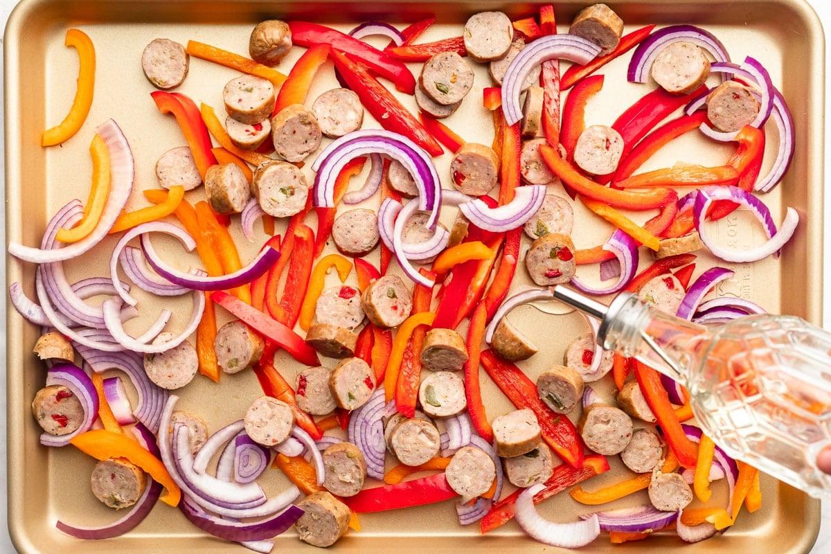 **Einfaches Backblechgericht mit Italienischer Wurst und Paprika** 3 Nahaufnahme der Zutaten, einschließlich in Scheiben geschnittener Wurst und bunter Paprika