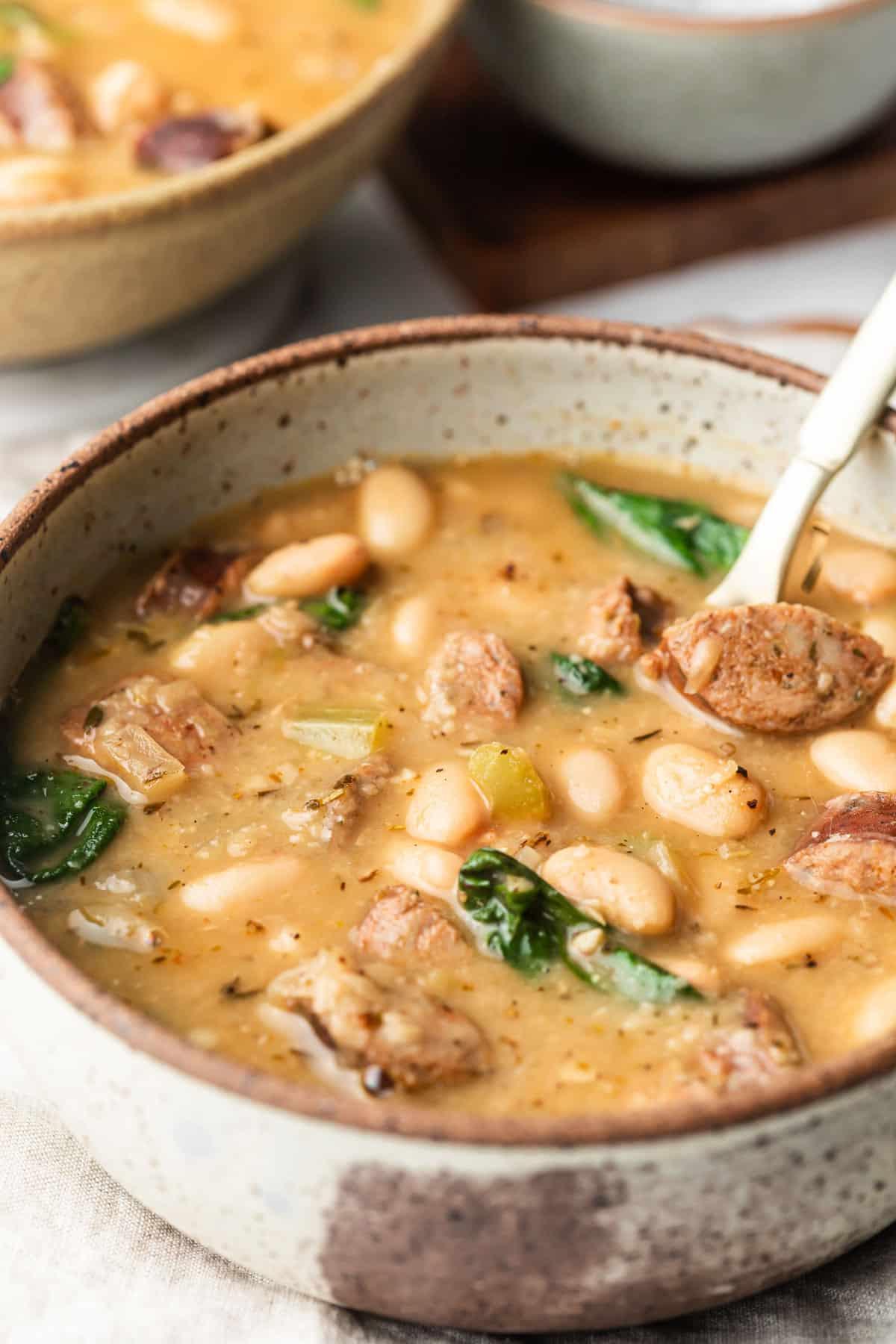 Einfache Wurst- und Weiße-Bohnen-Suppe 3 Nahaufnahme von ungekochten Zutaten: Wurstscheiben, Zwiebeln, Sellerie, Knoblauch und Dosen-Cannellini-Bohnen.
