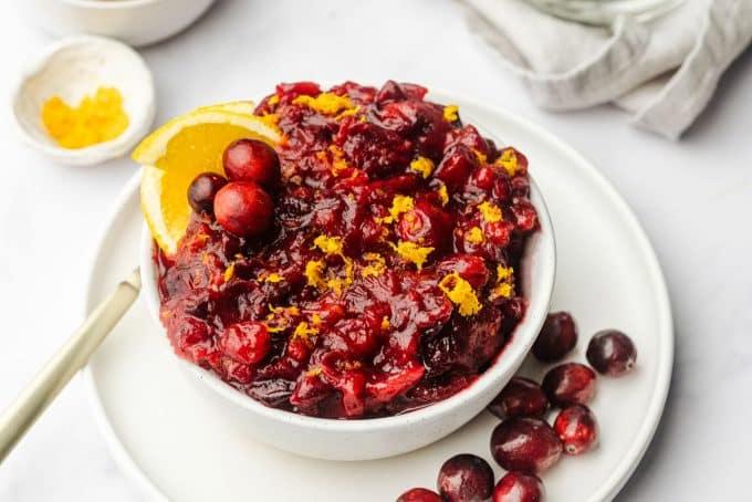 Nahaufnahme von Preiselbeeren, Orangenscheiben und einer Zimtstange, Zutaten für die Preiselbeersauce