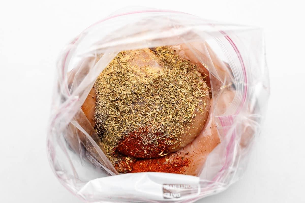 Eine Hand, die Hähnchenteile in einer Honig-Balsamico-Marinade in einem wiederverschließbaren Beutel hält