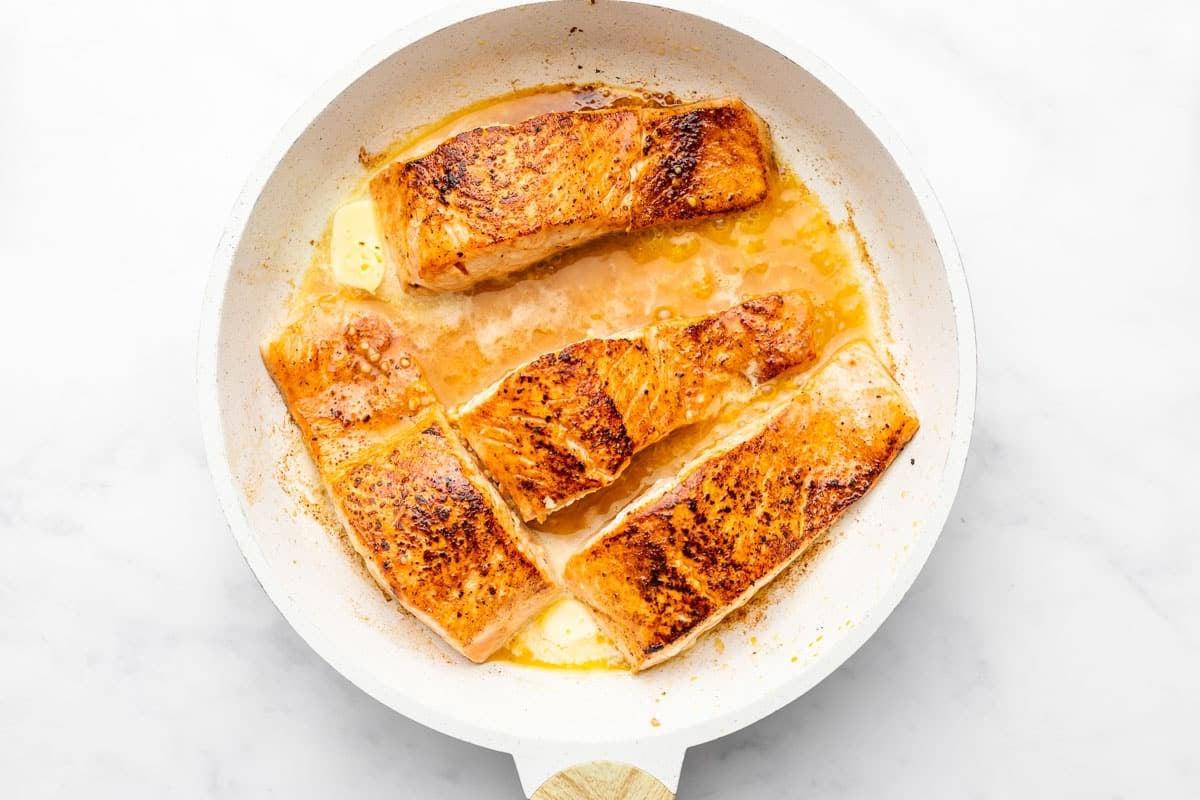 Einfacher scharf angebratener Chipotle-Limetten-Lachs 4 Ein Stück gebratener Lachs in einer Pfanne, beträufelt mit einer Butter-Knoblauch-Limetten-Sauce.