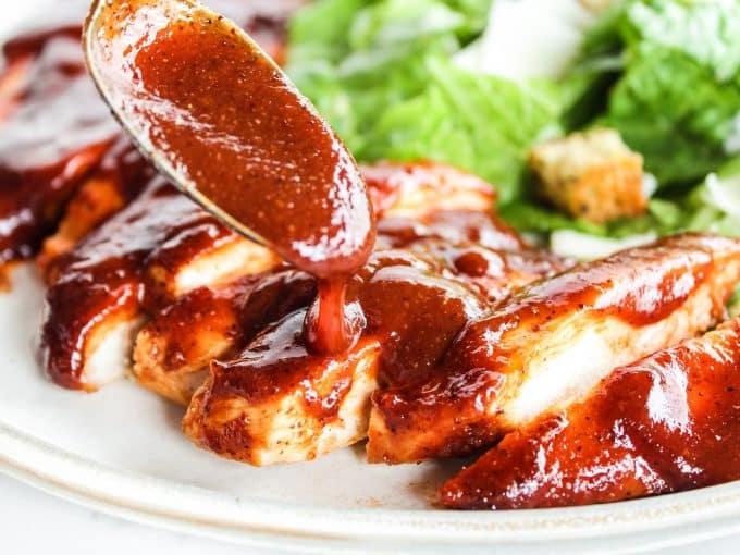 Ofengebackenes Barbecue-Hähnchen 4 Dünn geschnittene Hähnchenbrust-Cutlets bereit zum Belegen mit Sauce in einer Auflaufform.