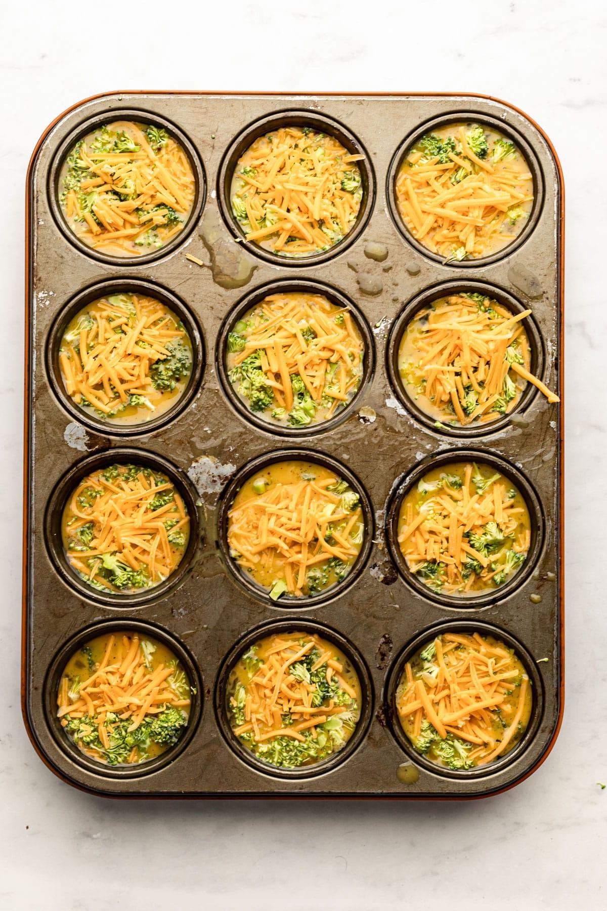 Brokkoli-Cheddar-Eier-Muffins 4 Goldbraun gebackene Brokkoli-Cheddar Eier-Muffins in einer Muffinform, perfekt aufgegangen und bereit zum Herausnehmen.