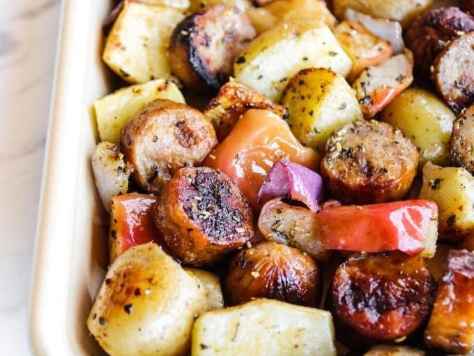 Wurst mit Äpfeln und Kartoffeln vom Blech 4 Detailansicht des fertig gebackenen Blechgerichts mit glänzender Wurst und goldbraunen Kartoffeln