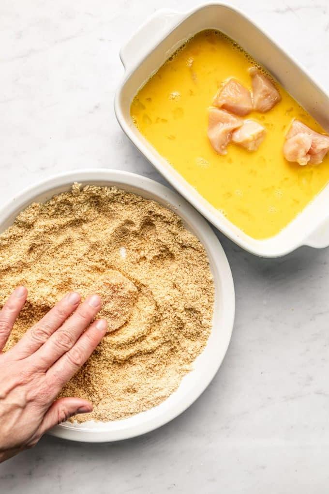 Gebackene Mandel-Hähnchen-Nuggets 4 Detailaufnahme von Hähnchen-Nuggets, die mit Mandelmehl paniert und auf ein Backblech gelegt werden