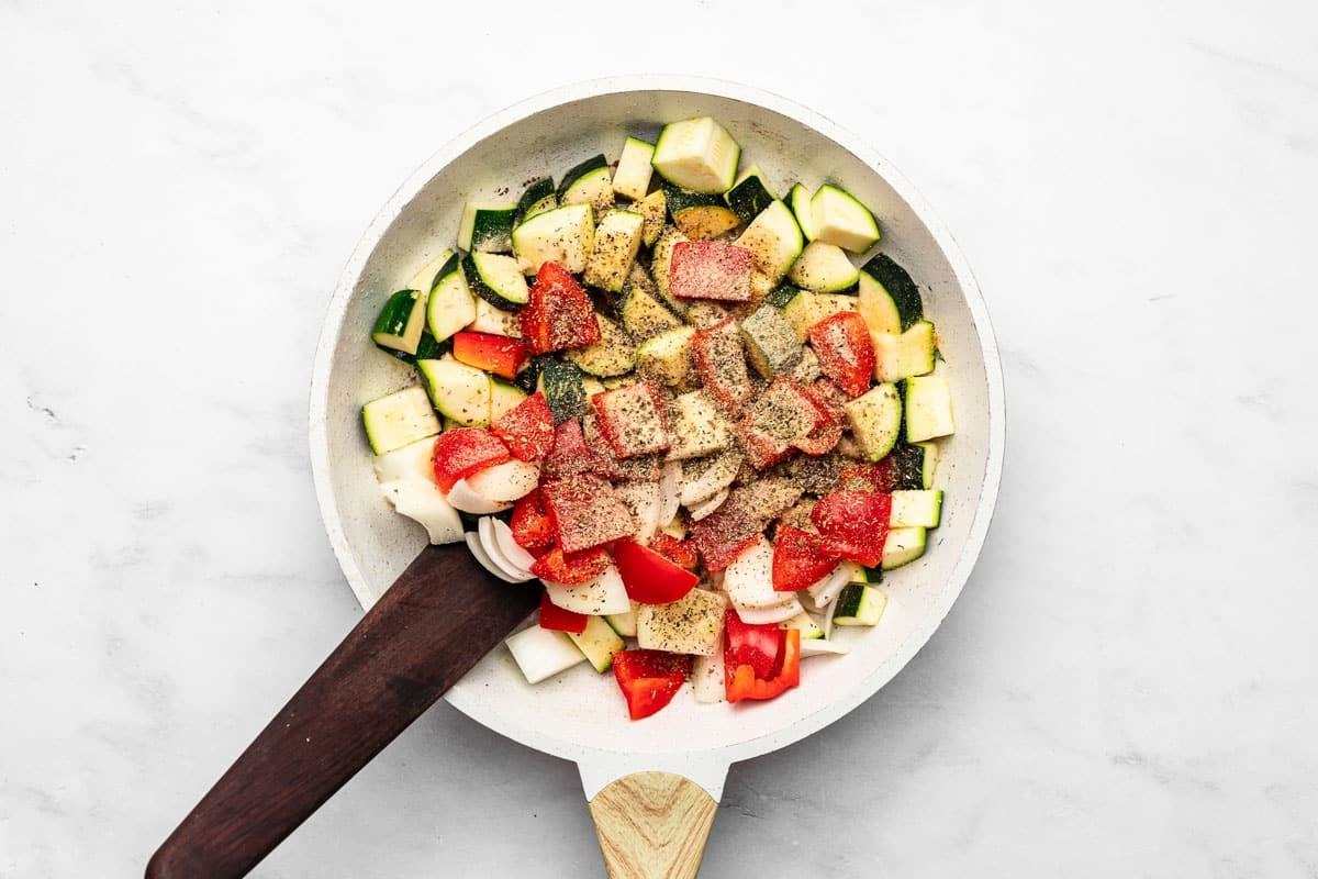 **20-Minuten-Wurst-Zucchini-Pfanne** 4 Ein Detailbild der Zucchini-Wurst-Pfanne, die in einer großen Pfanne auf dem Herd köchelt.