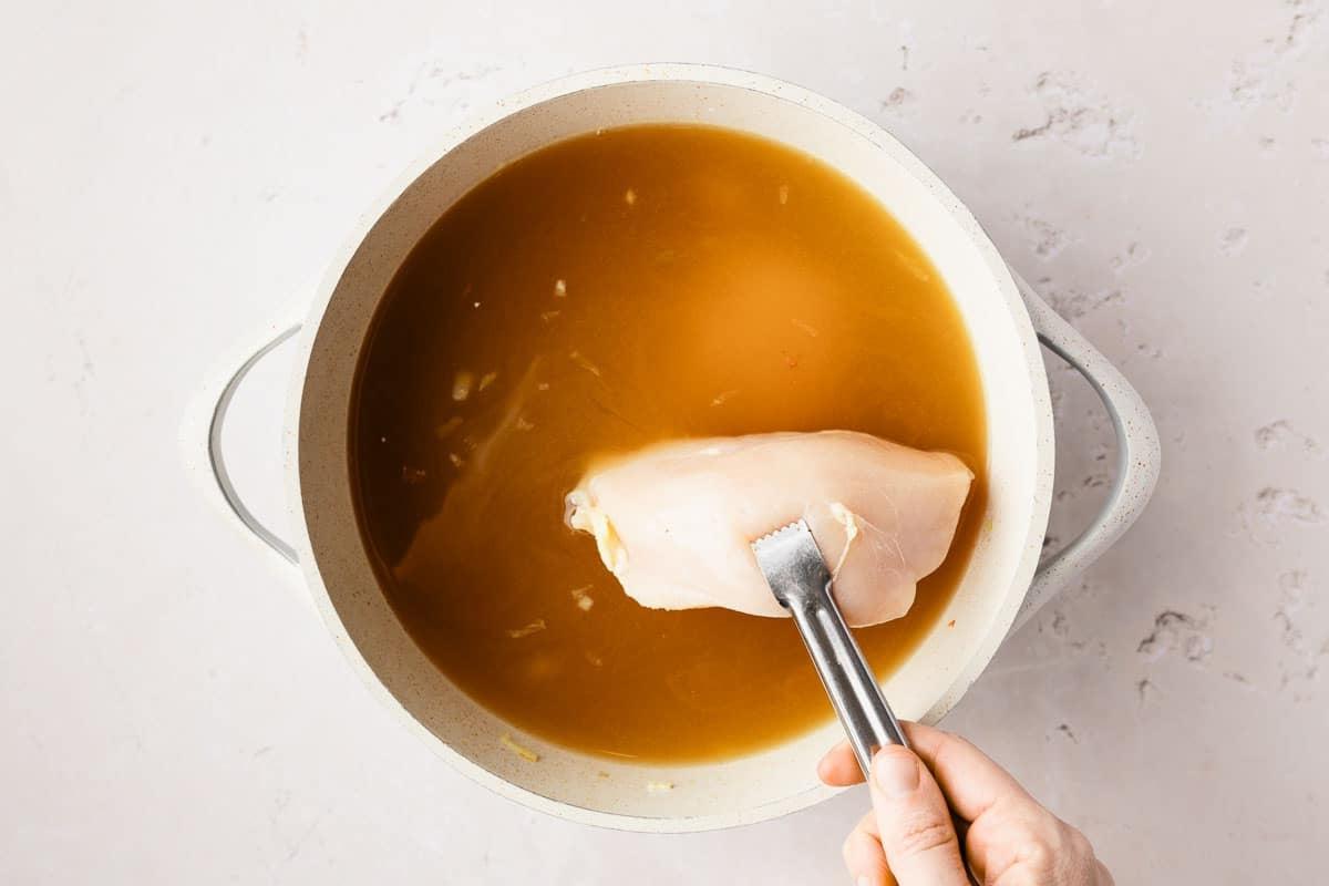 Cremige Hähnchennudelsuppe 4 Zutaten für cremige Hühnernudelsuppe: Frisches Gemüse, Hühnchen und Nudeln auf einem Schneidebrett
