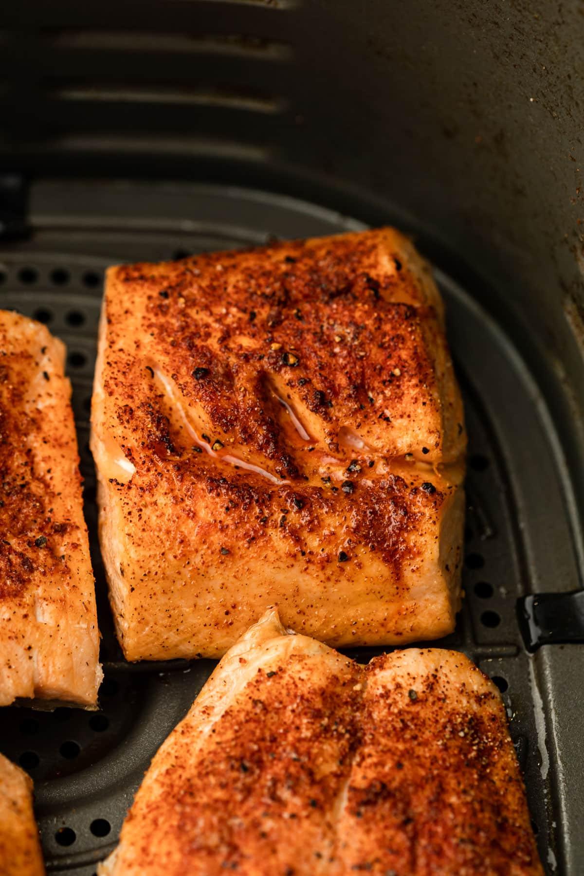 **Heißluftfritteusen-Lachs** 4 Ein Detailaufnahme von zartem, perfekt gegartem Lachs, der bereit ist, mit einer Gabel zerteilt zu werden, und die blättrige, saftige Textur des Fleisches zeigt, das darauf wartet, genossen zu werden.