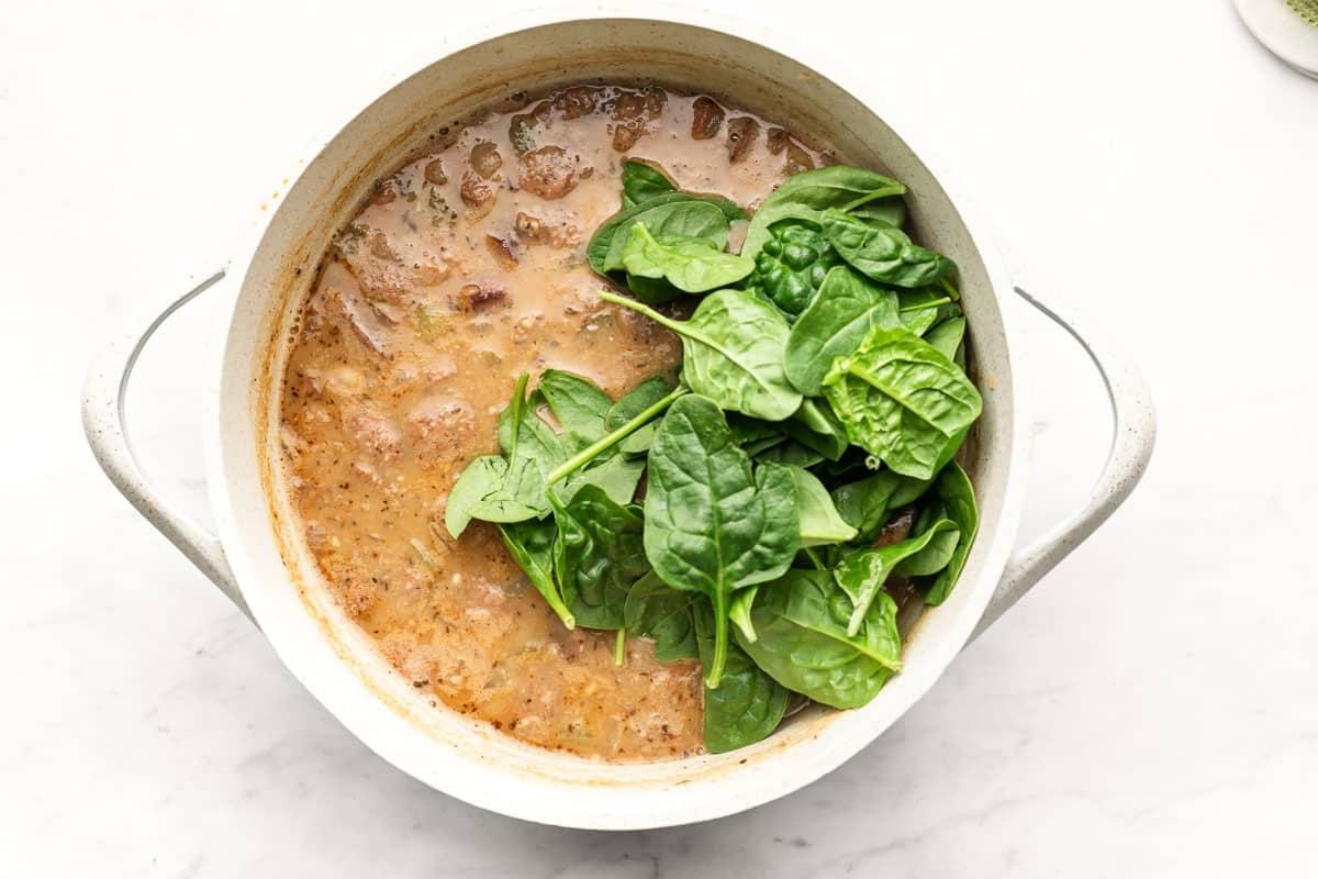 Einfache Wurst- und Weiße-Bohnen-Suppe 4 Ein Löffel mit cremiger weißer Bohnensuppe mit Wurstscheiben, bereit zum Servieren.