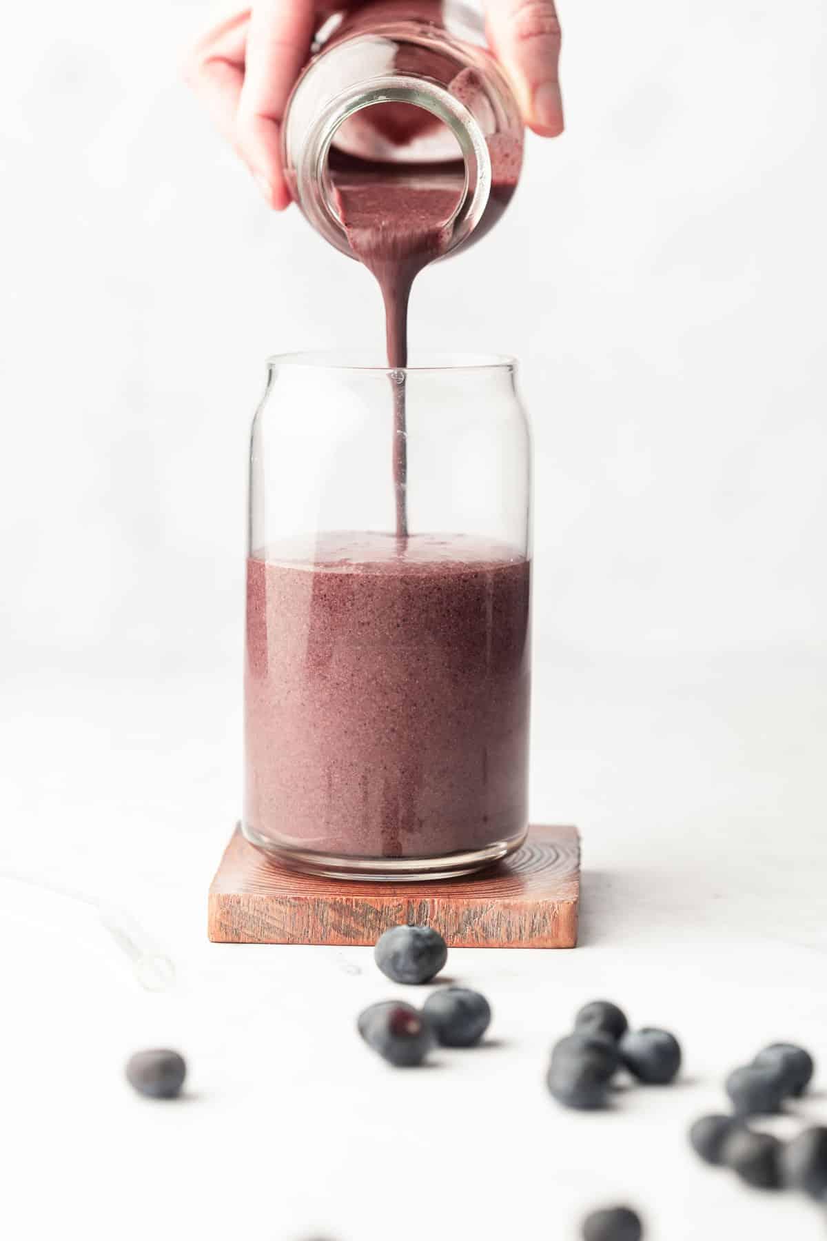 Ein köstlicher Blaubeer-Mandel-Smoothie, fertig zum Genießen, mit frischen Blaubeeren als Garnitur in einem modernen Glas.