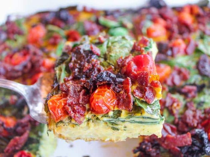 Nahaufnahme der Zutaten des BLT Frühstücksauflaufs vor dem Backen: Speck, Tomaten, Spinat und Kartoffeln