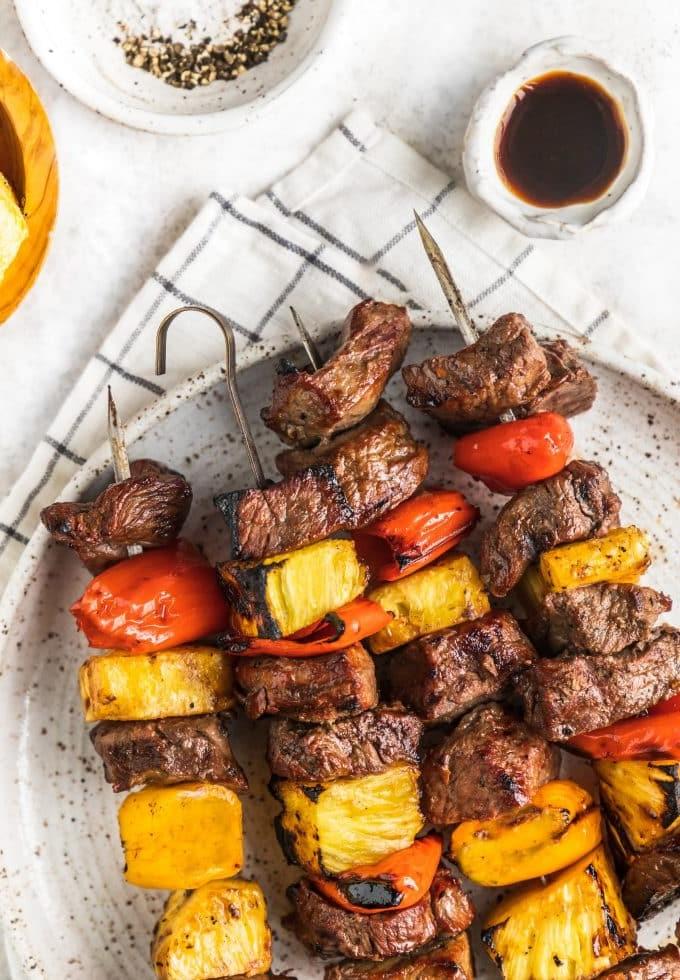 Hawaii-Steak-Spieße 5 Fertig gegrillte hawaiianische Steak-Spieße auf einem Servierbrett mit frischer Petersilie