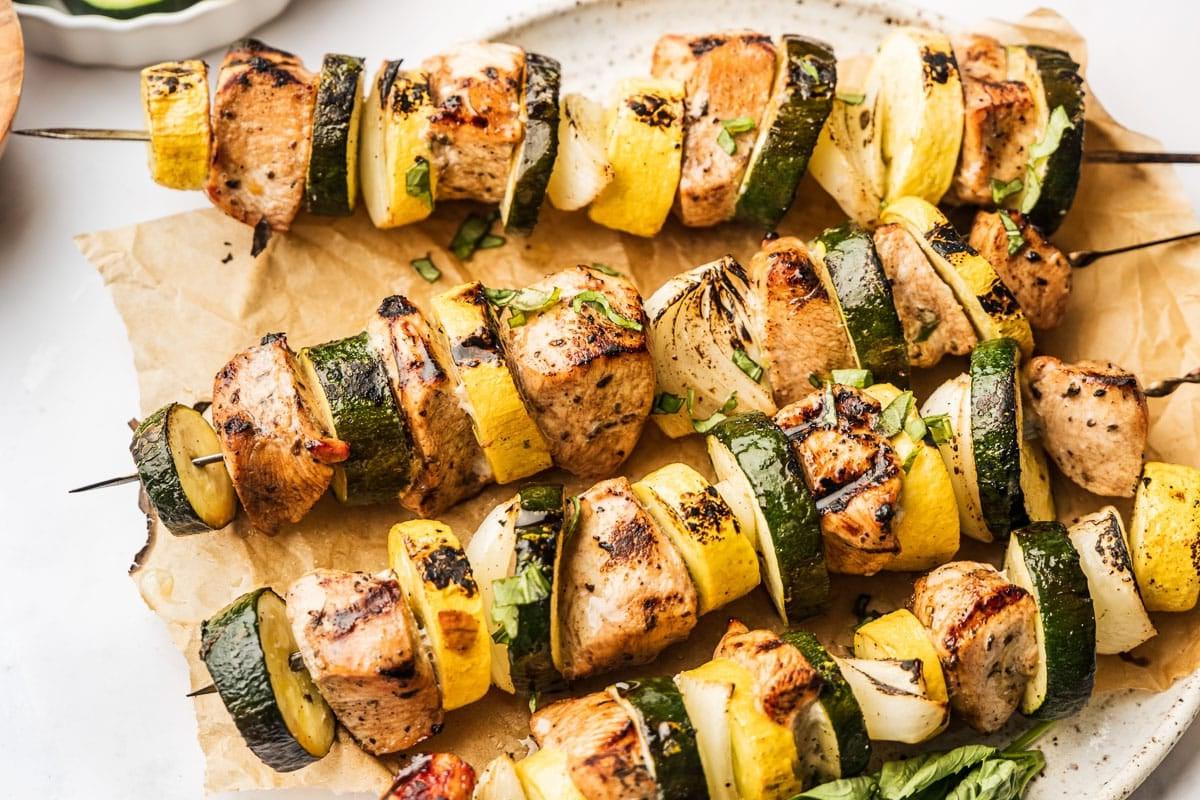 Appetitliche gegrillte Hähnchenspieße auf einem Servierteller, mit leichtem Grillmuster.