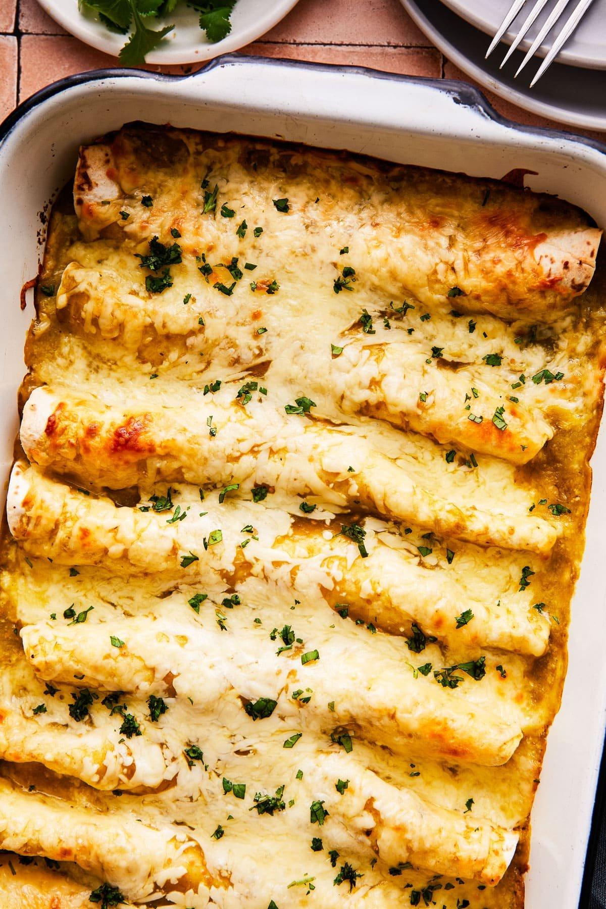 Servierfertige Salsa Verde Hähnchen-Enchiladas, mit frischen Toppings garniert