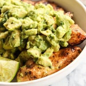 Gegrilltes Hähnchen mit Chili-Limetten-Marinade und Avocado-Topping auf einem Holzbrett.