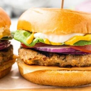 Die besten Hähnchenhackfleisch-Burger 6 Nahaufnahme eines saftigen Hähnchen-Hackfleisch-Burgers mit frischen Kräutern