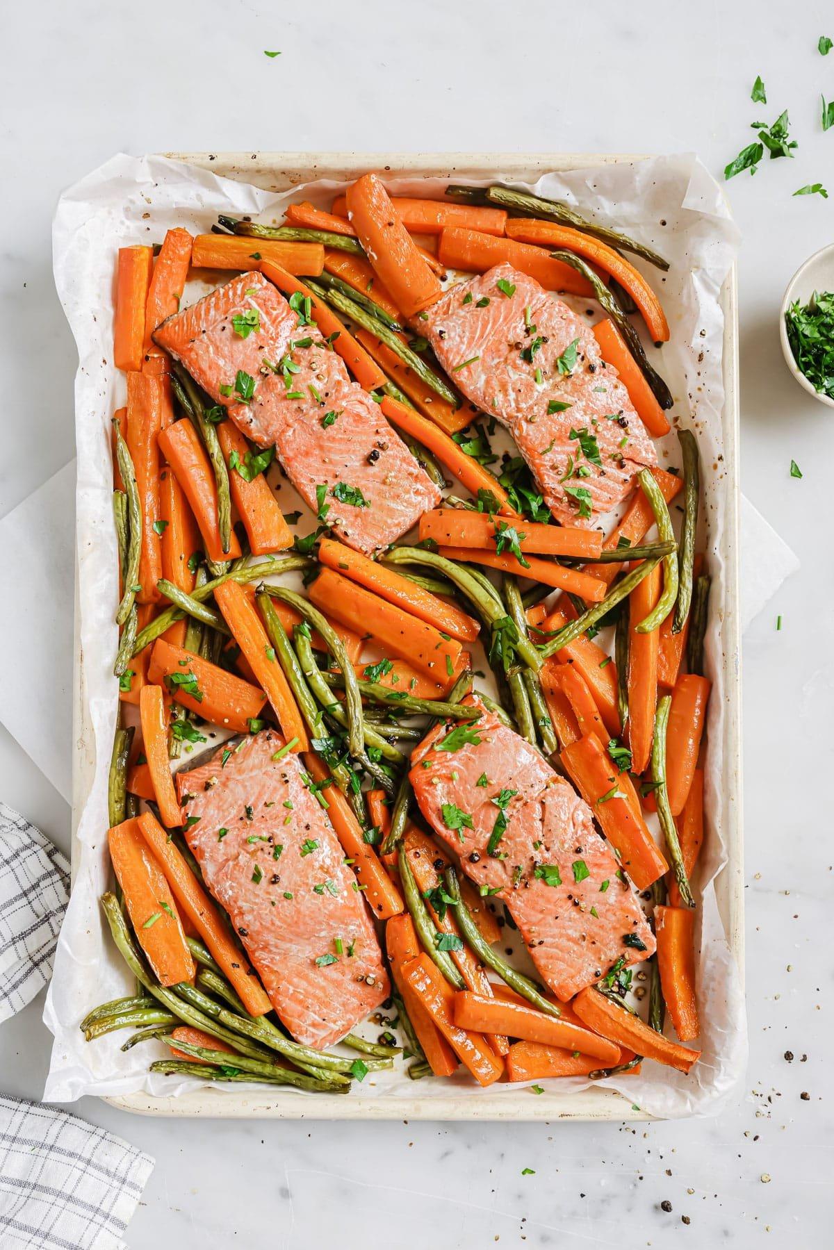 Fertiger Zitronen-Pfeffer-Lachs mit gerösteten Karotten und grünen Bohnen auf einem Teller, servierbereit