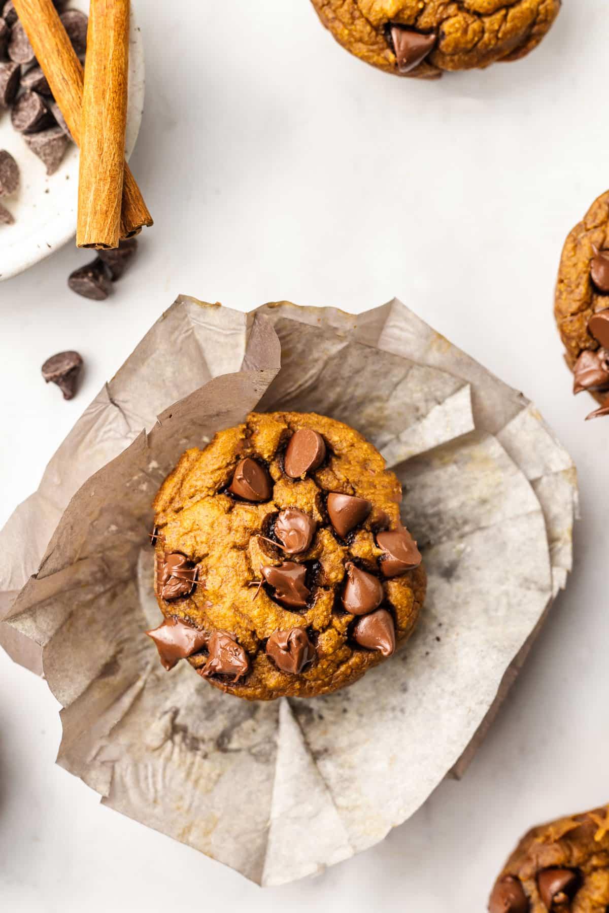 Ein Korb voller goldbrauner Kürbis-Haferflocken-Muffins mit sichtbaren Schokostückchen