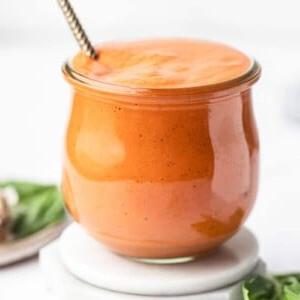 5-Minuten-cremige geröstete rote Paprika-Soße 7 Nahaufnahme einer cremigen gerösteten Paprikasauce in einer kleinen weißen Schüssel mit frischem Basilikumgarnitur.
