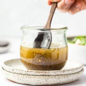 Einfaches selbstgemachtes italienisches Salatdressing 7 Fertiges italienisches Dressing im Glas und daneben ein kleiner Salat