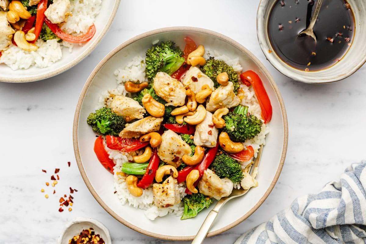 Einfaches Cashew-Hähnchen vom Blech 7 Serviertes Ofenblech-Cashew-Hähnchen in einer Schüssel mit Reis und frischer Petersilie
