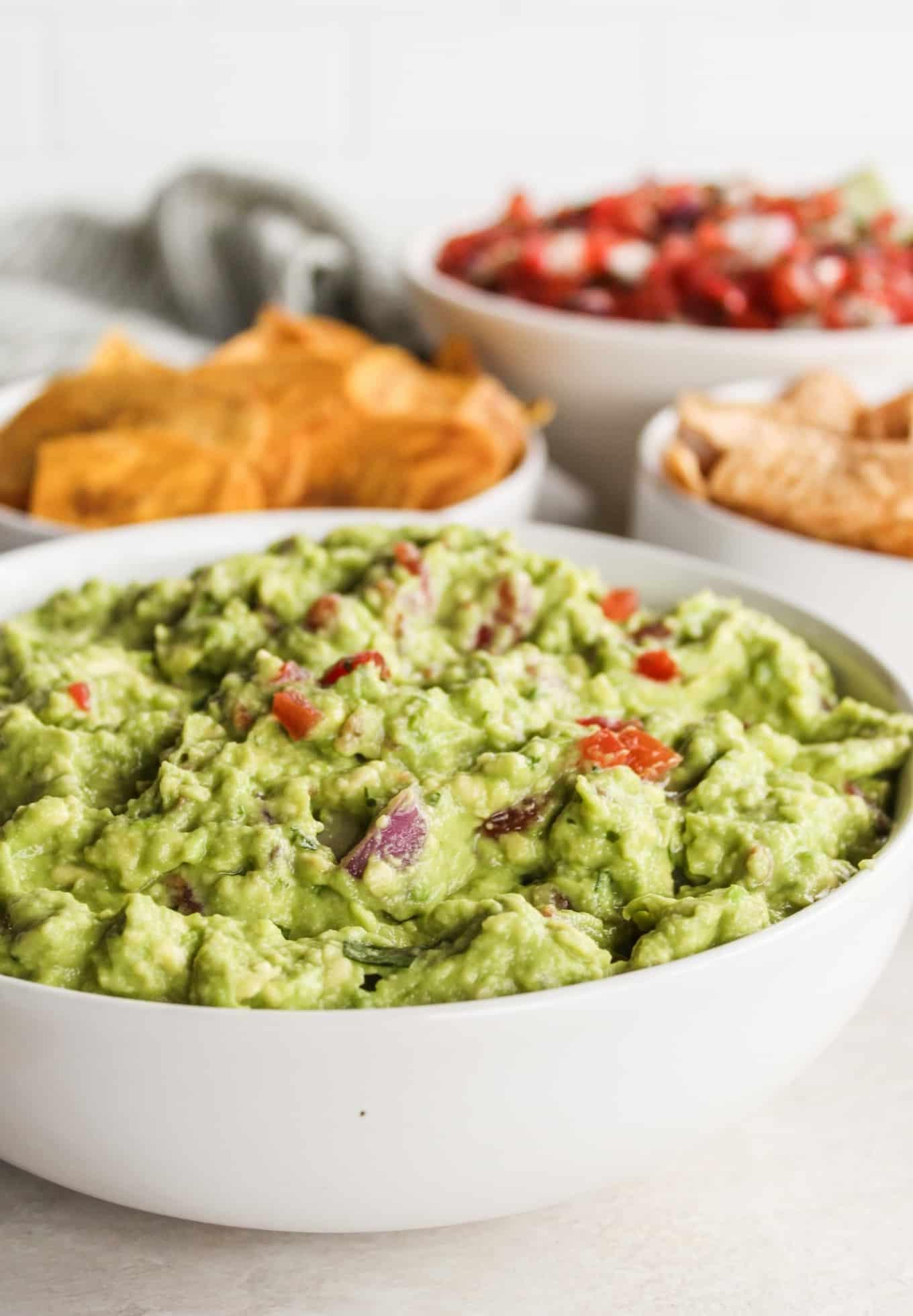 Hausgemachte Guacamole mit frischen Avocados, Zwiebeln, Tomaten und Koriander, bereit zum Servieren