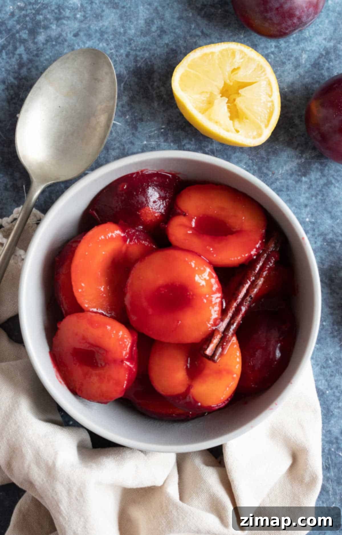 Εύκολη Κομπόστα Δαμάσκηνων 2 Stewed plums with cinnamon in a grey bowl.
