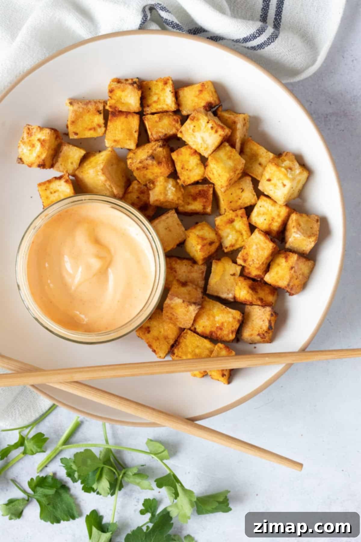 Τραγανό Τόφου Αέρος 2 Air fried tofu on a plate with a dipping sauce.