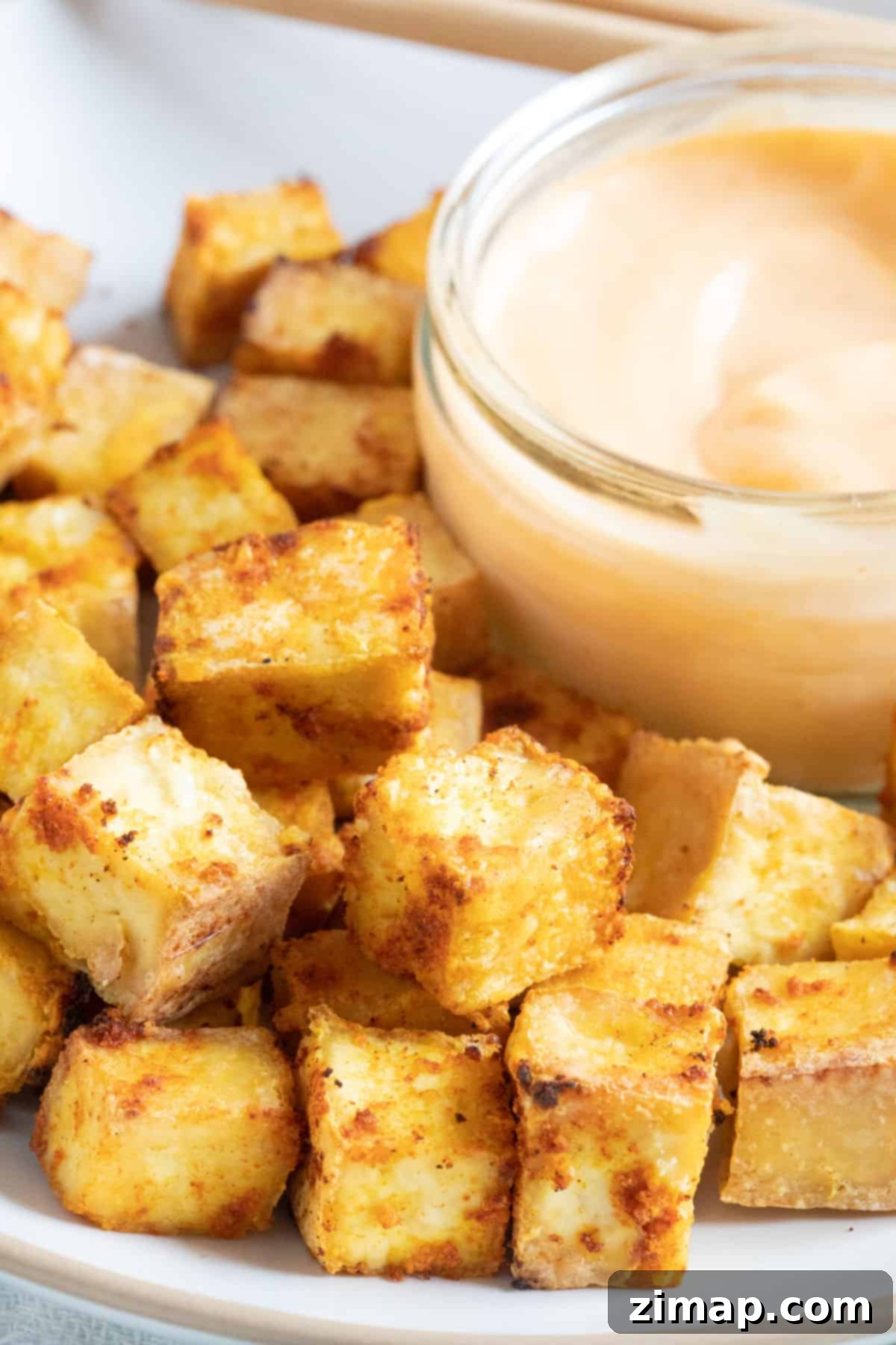 Τραγανό Τόφου Αέρος 5 Crispy golden air fryer tofu cubes on a plate.