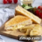 Τραγανό Τοστ Φριτέζας Αέρος 11 Cheese toastie made in an air fryer on a wooden board with crisps.